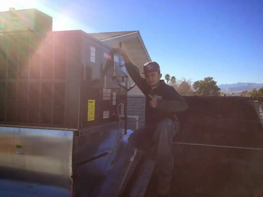 HVAC technician performing Air Duct Cleaning on a rooftop unit in Lumberton